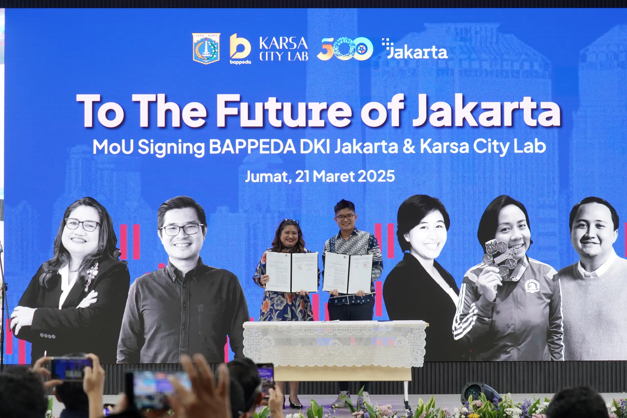 MoU signing ceremony between BAPPEDA DKI Jakarta and Karsa City Lab, featuring participants holding documents on stage.